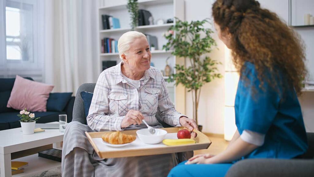 Older adults practice gentle balance exercises in a bright assisted living activity room.