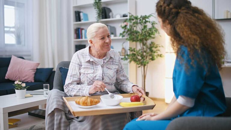 Older adults practice gentle balance exercises in a bright assisted living activity room.