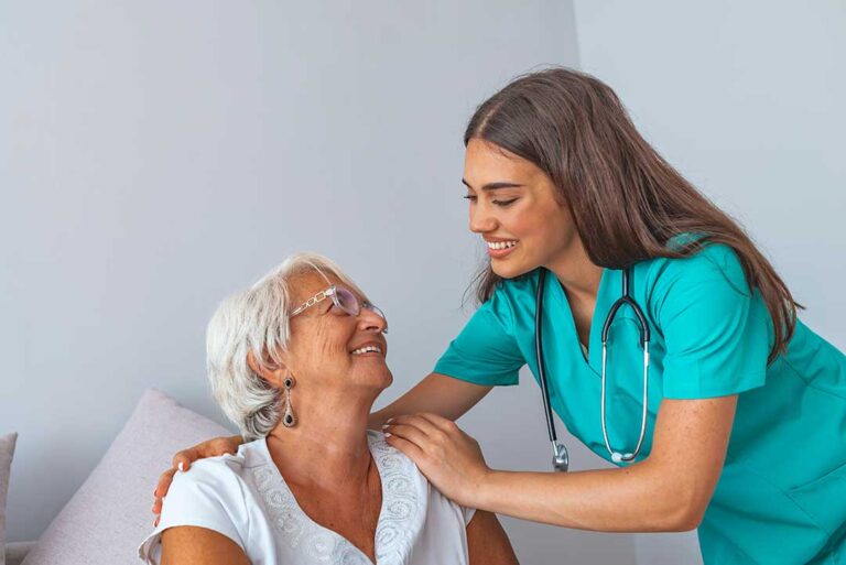 An older adult talking with a social worker in a warmly lit residential common area.